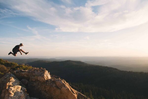 Dynamic image of a person making a bold jump across a mountain gap, representing the leap of faith churches take when selecting a cleaning service.