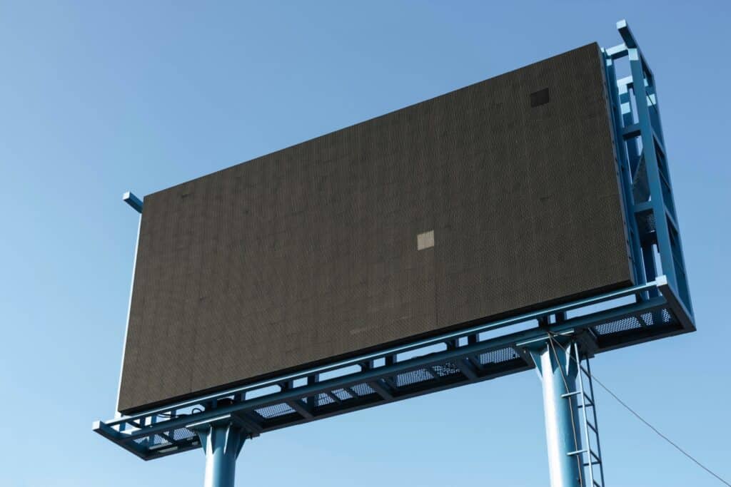 Empty billboard ready for an advertisement with a clear blue sky background.