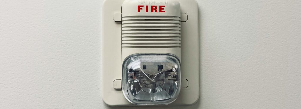 Wall-mounted fire alarm with strobe light, crucial for janitorial staff’s emergency response training