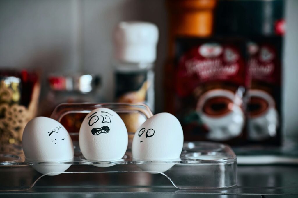 Three eggs with funny faces drawn on them in an egg holder