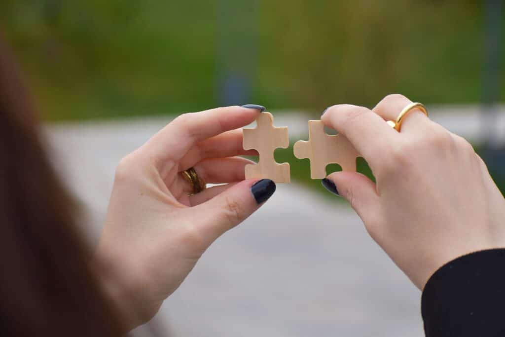 Hands holding two puzzle pieces fitting together, representing the strategy of raising prices for cleaning services