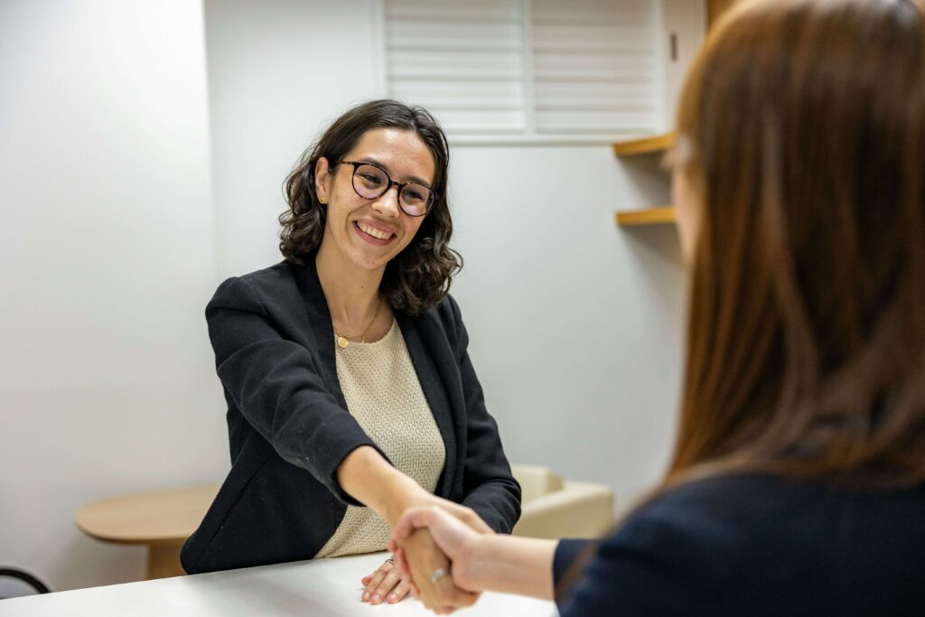 A smiling interviewer shaking hands with a candidate during a cleaning service job interview.