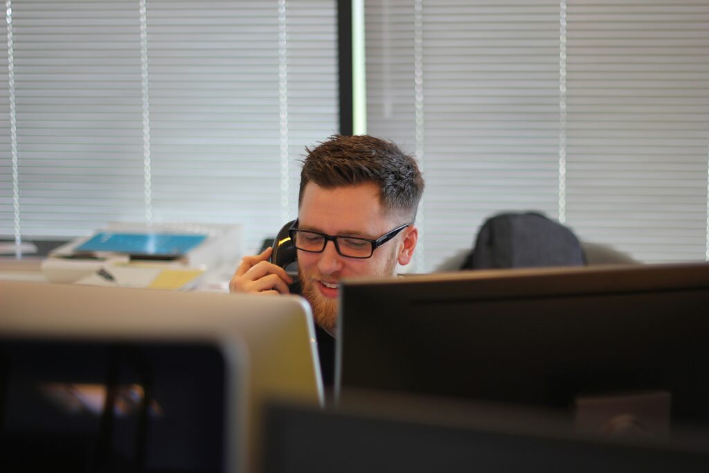 Customer service representative handling a phone call at a cleaning business office.