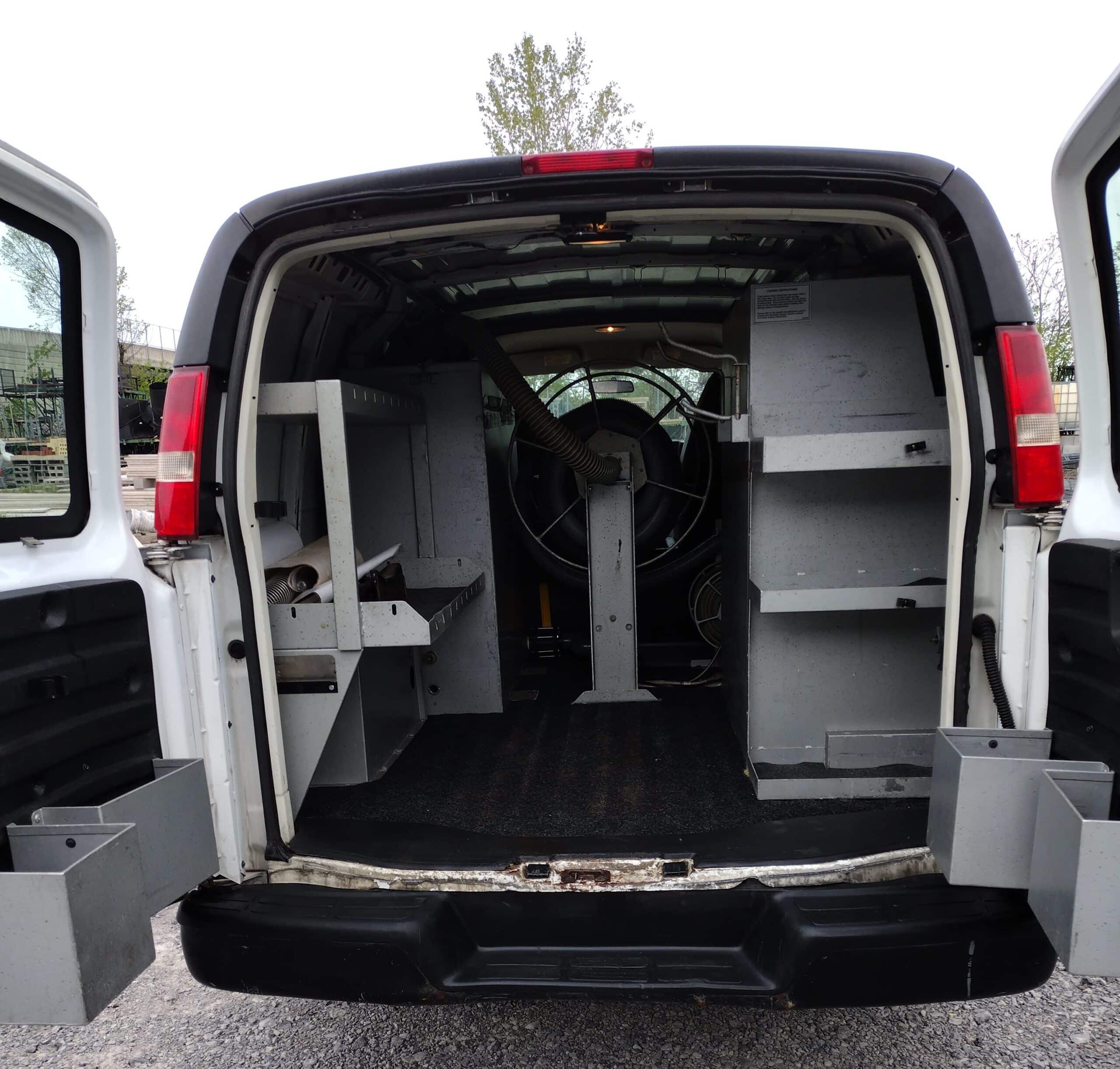 Interior view of a cleaning service van with mounted hose reel and storage, illustrating equipment setup considerations for leasing or buying.