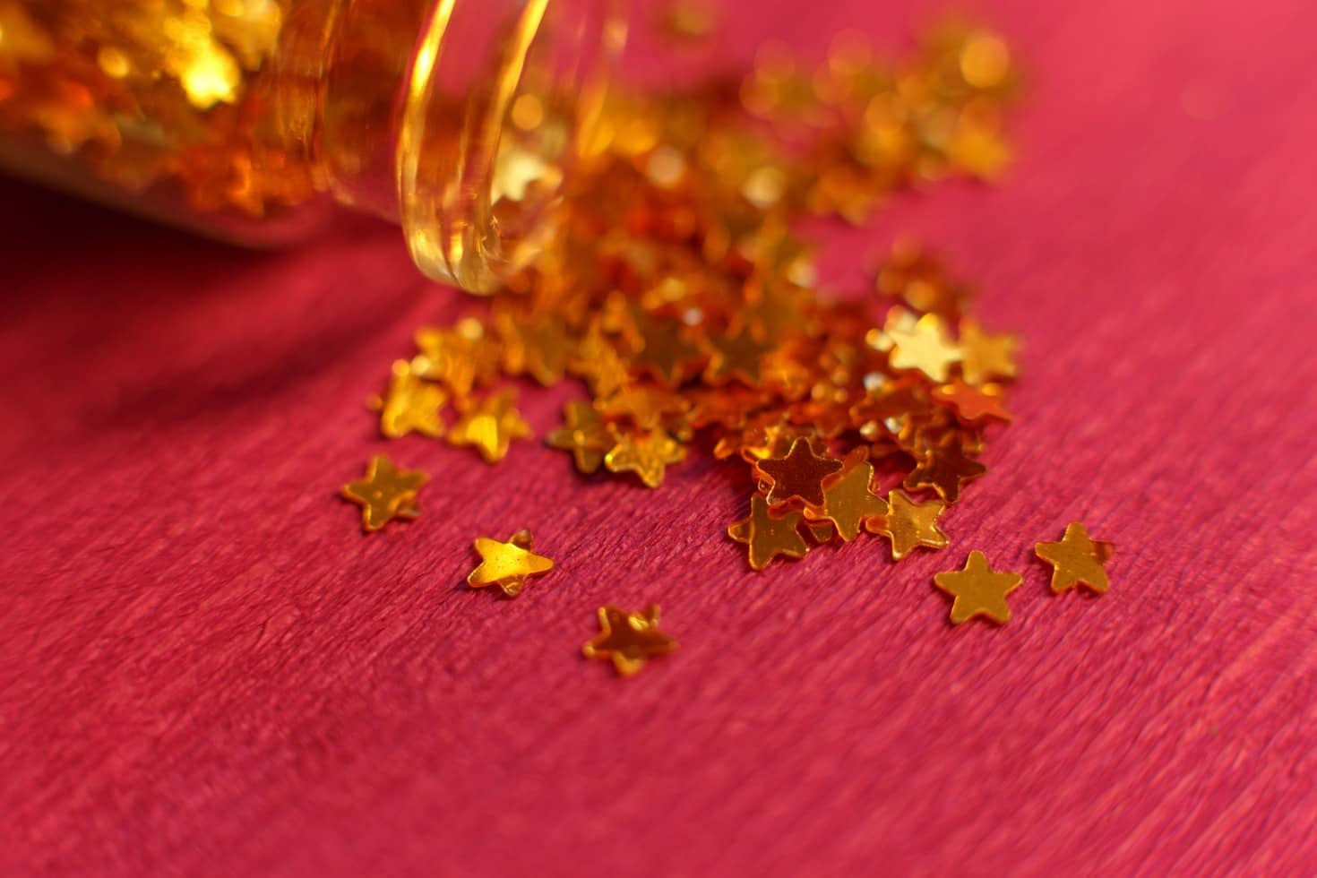 Gold stars spilling from a jar onto a pink background, symbolizing positive customer reviews for cleaning businesses.